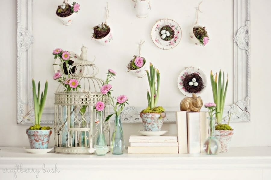 teacups and birdcages with plants on mantel