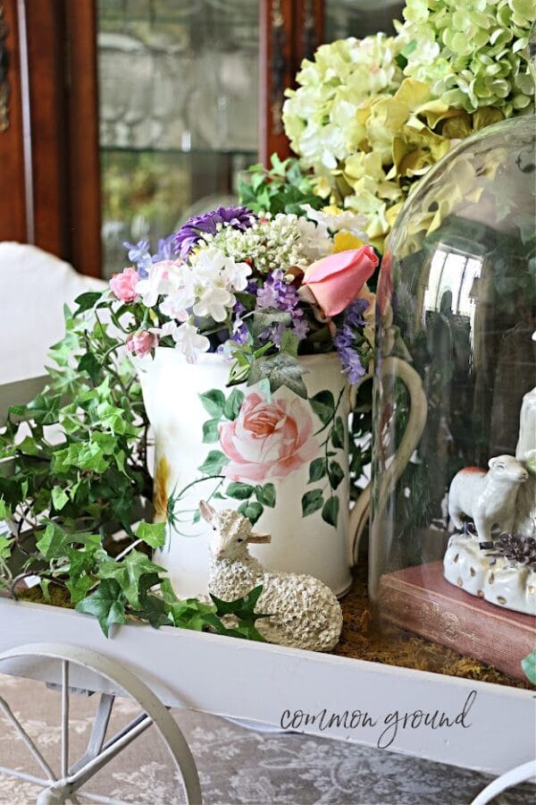 vintage pitcher with flowers and greenery. Small labb inside a cloche and in a wheelbarrow