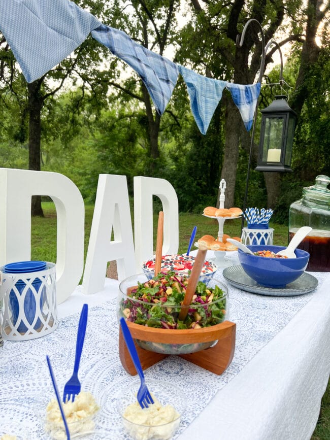 white table outside with DAD letters and salad bowls