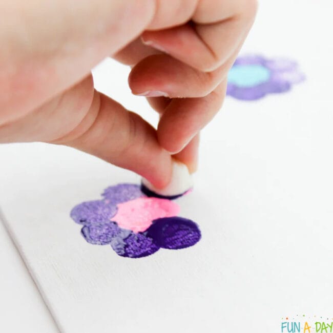 childs hand with mini marshmallow making flowers with paint