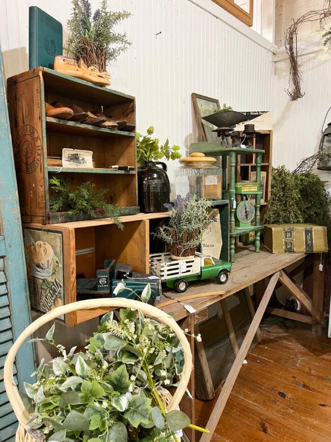 stacked crates with green vintage pieces and a truck, plants, luggage