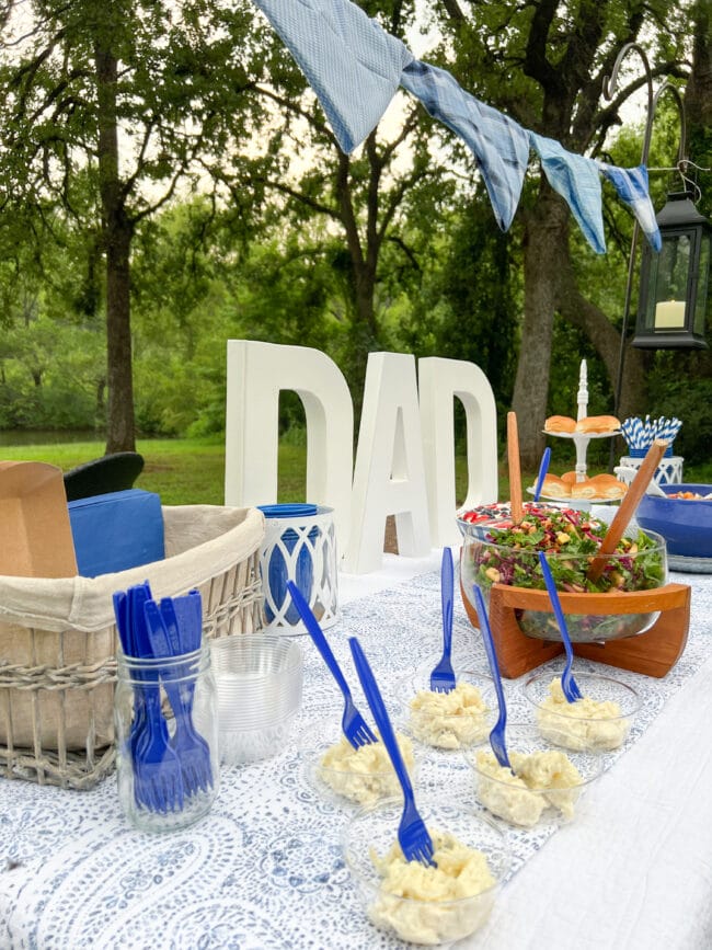 side view of DAD table with food in small cups and blue forks and salads