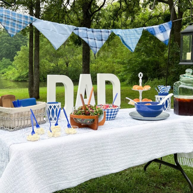 white table with DAD and blue fabric garland and food at the lake