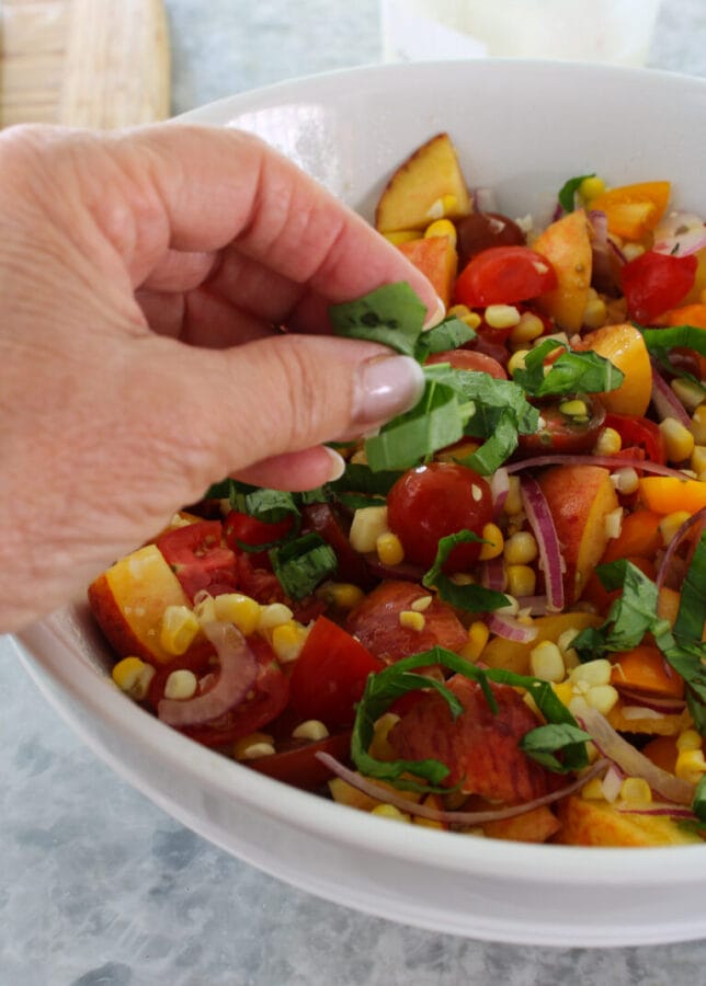 summer salad with hand sprinkling a green garnish