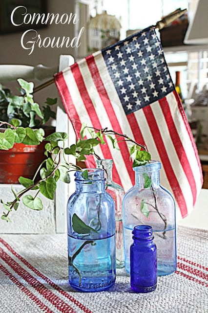 vintage blue bottles with ivy and a flag behind them