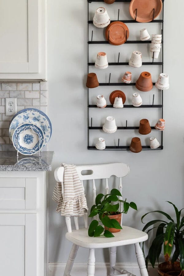 wall rack with garden pots, a white chair with plant and blue and white dishes on the kitchen counter