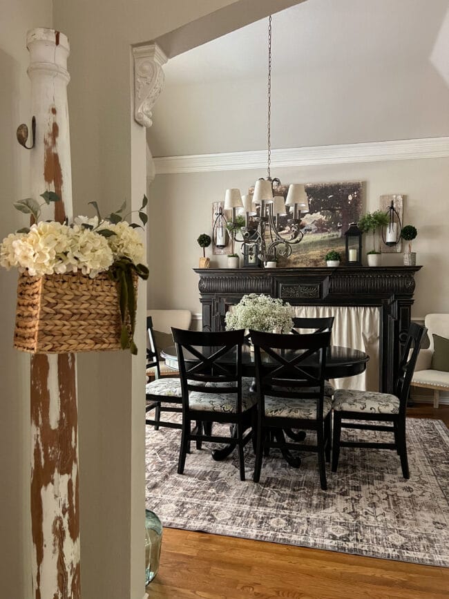 entry to a dining rom with black furniture and a column with a basket of flowers at the door