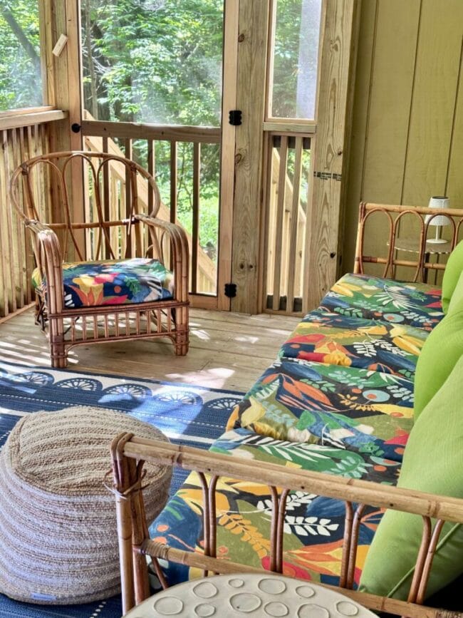 screened porch with sofa and chair with a tropical print cushions