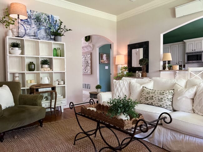 family room with white sofa, green chair, cubby shelf and iron bench coffee table