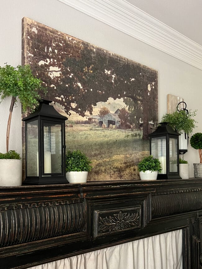 black mantel with farm print and topiaries with lanterns