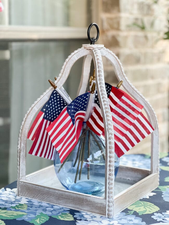 white beaded open lantern with a blue vase and flags inside