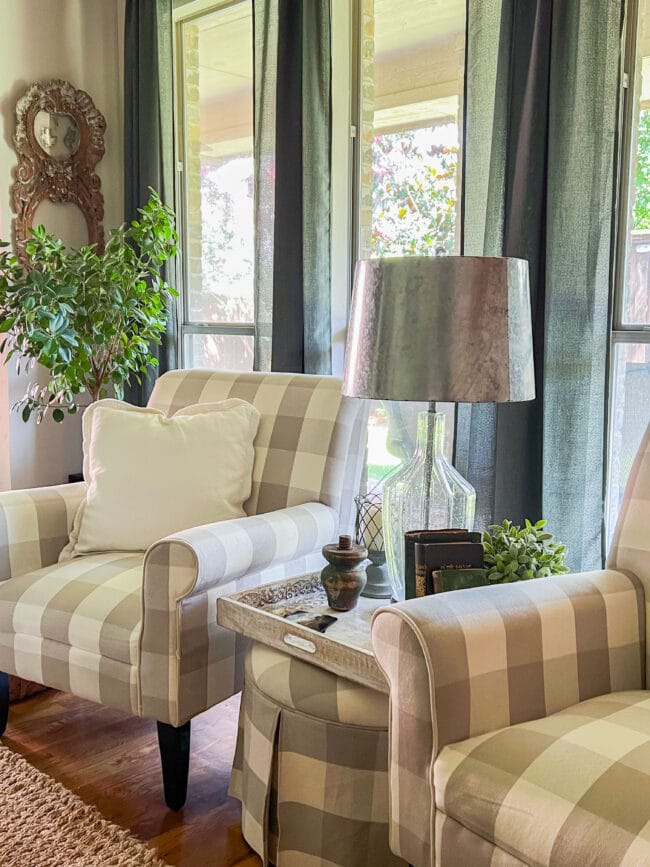 gray and white checked chairs in front of windows with a matching ottoman table in between and a lamp