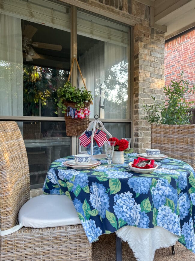 outdoor table with blue and green hydrangea tablecloth and patriotic decor