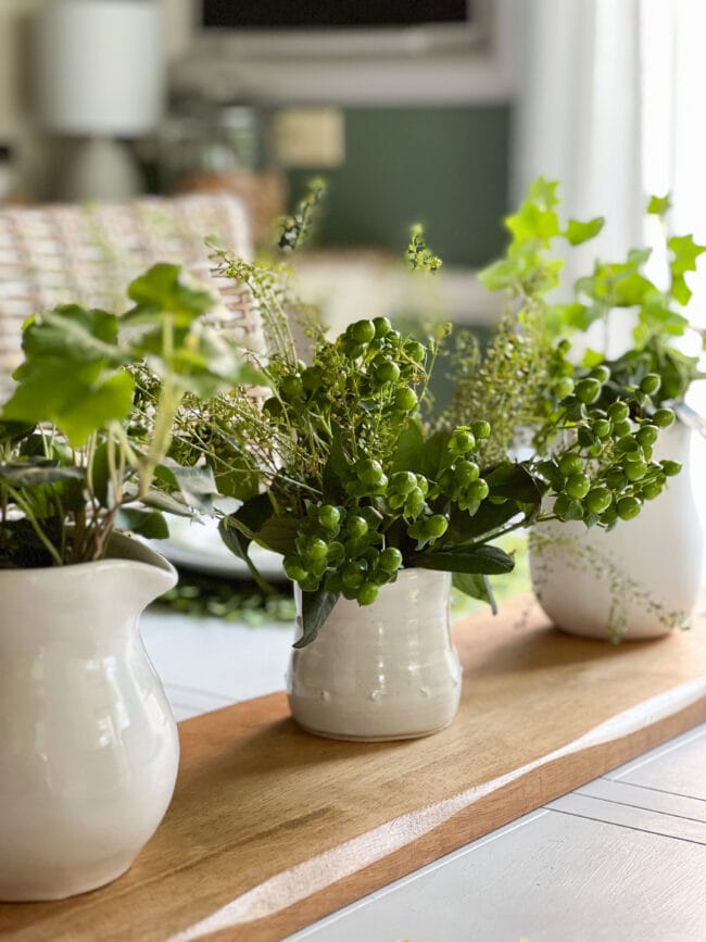 3 white pots with plants sitting on a breadboard as a centerpiece