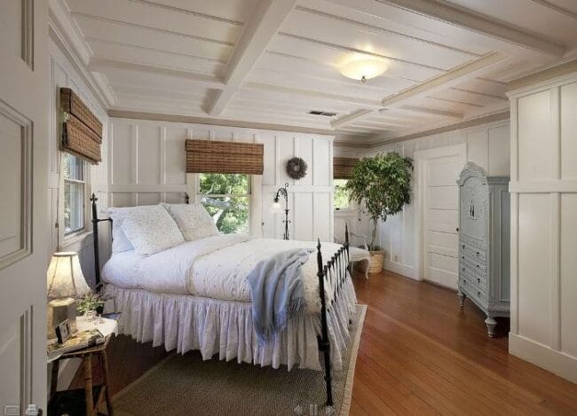 iron bed angled in corner with country bedding and blue armoire