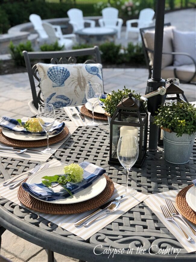 patio table with green hydrangeas, lanterns and a firepit in background