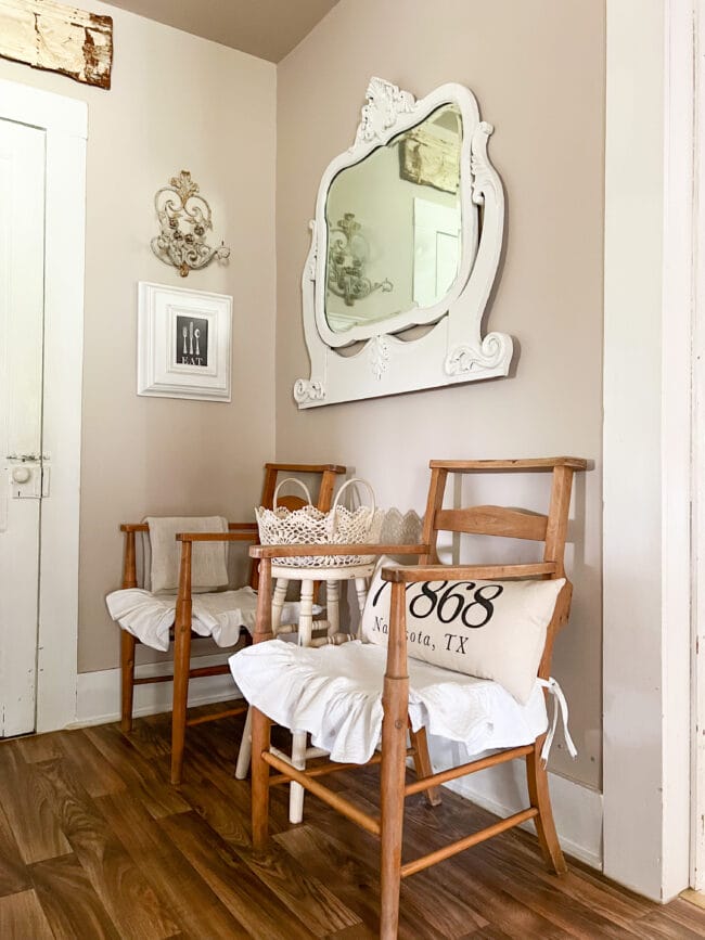 2 vintage pew chairs with stool in between and dresser mirror on wall