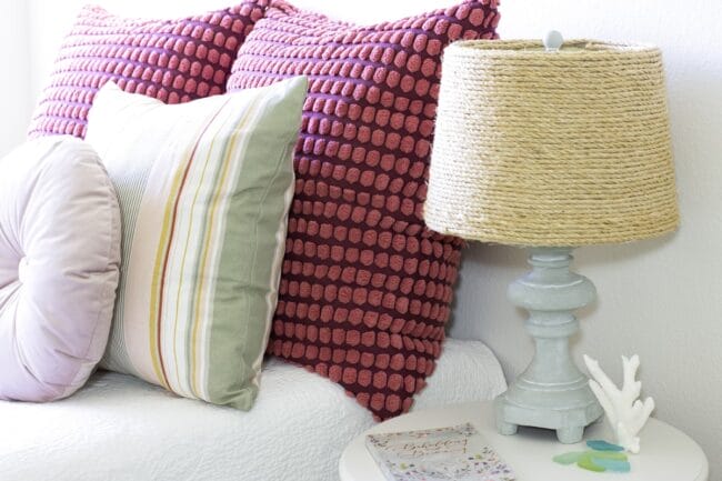 red pillows with a blue and rattan lamp sitting on a side table next to sofa