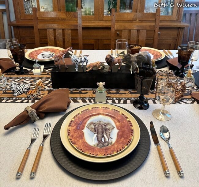 jungle theme table setting with animal plates, brown napkins and gold silverware