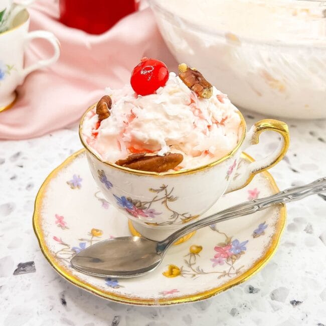 antique tea cup with blue and pink flowers and inside is a fruit salad