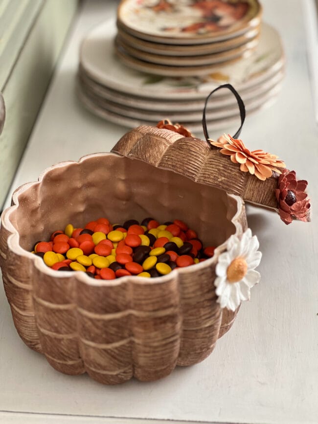 wood look pumpkin with paper flowers and open lid with Reese's Pieces inside