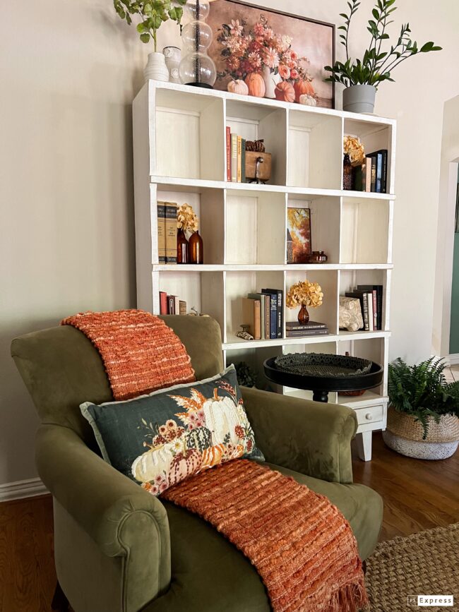 green velvet chair with white cubbies behind it and small black side table