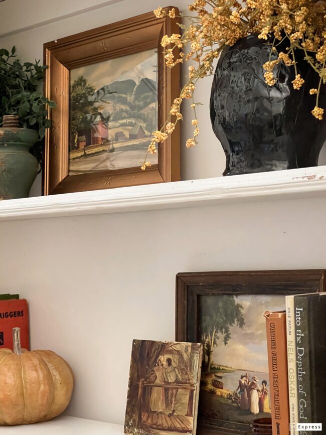 hutch shelves with books, paintings, pumpkins and faux stems. All in fall colors.