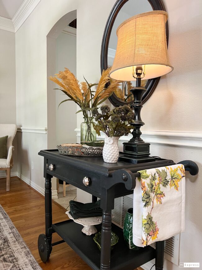 black antique teacart with a lamp, hanging tablecloth and faux stems