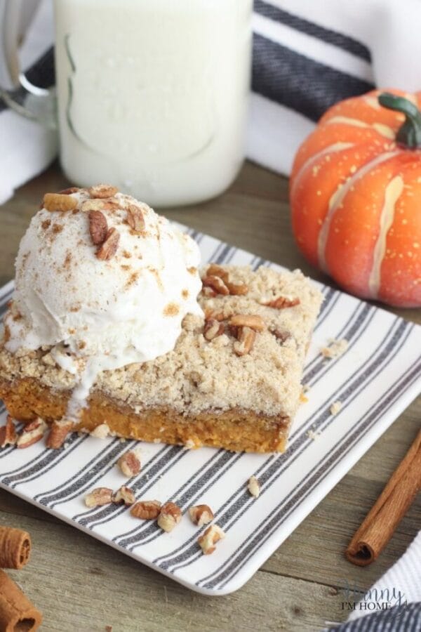 pumpkin dump cake on striped plate with vanilla ice cream and pecans