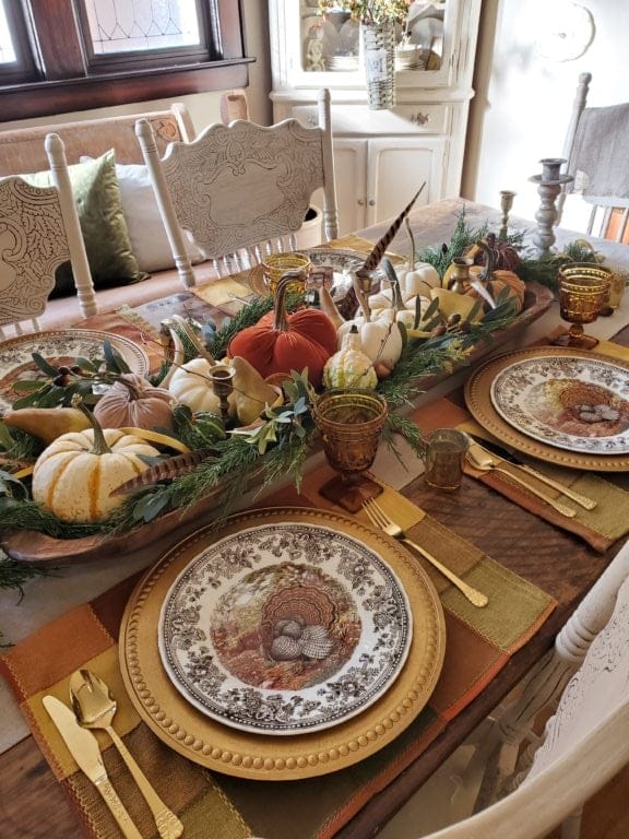 Thanksgiving tablescape with pumpkins and feathers as a centerpiece and brown transferware