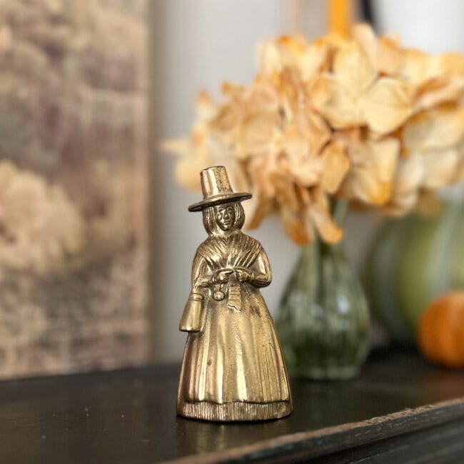 Small brass Pilgrim bell with gold flowers in background