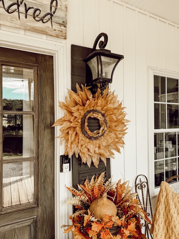 corn husk wreath hanging on shutter on porch