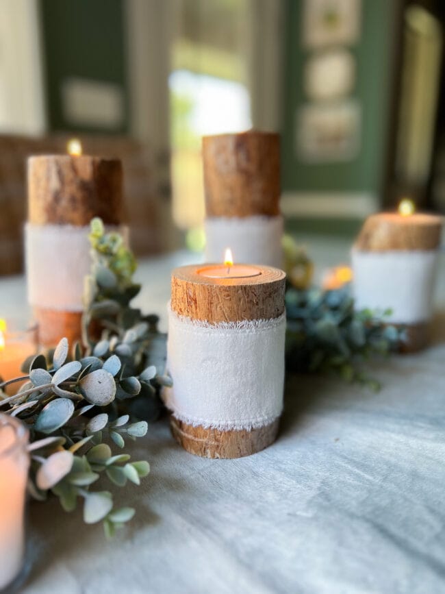 grouping of log candles with white ribbon and tea lights