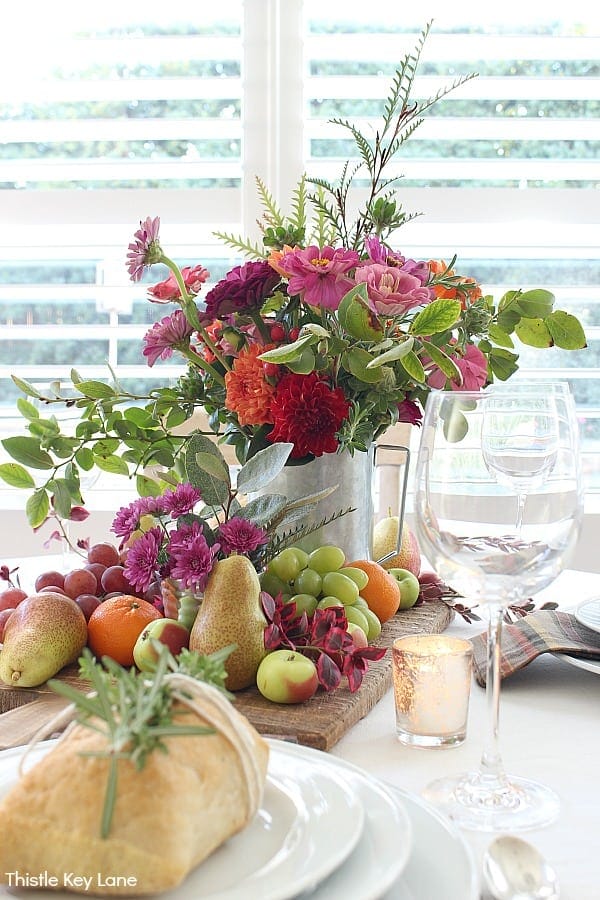 white pitcher with flowers and fruit as a centerpiece 