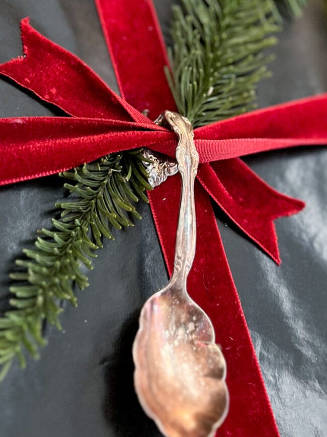 close up of black gift box with red velvet ribbon and a vintage silver spoon