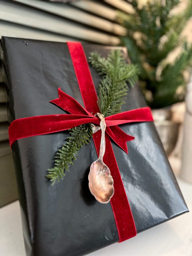 black gift box with a silver spoon, red velvet ribbon and real greenery