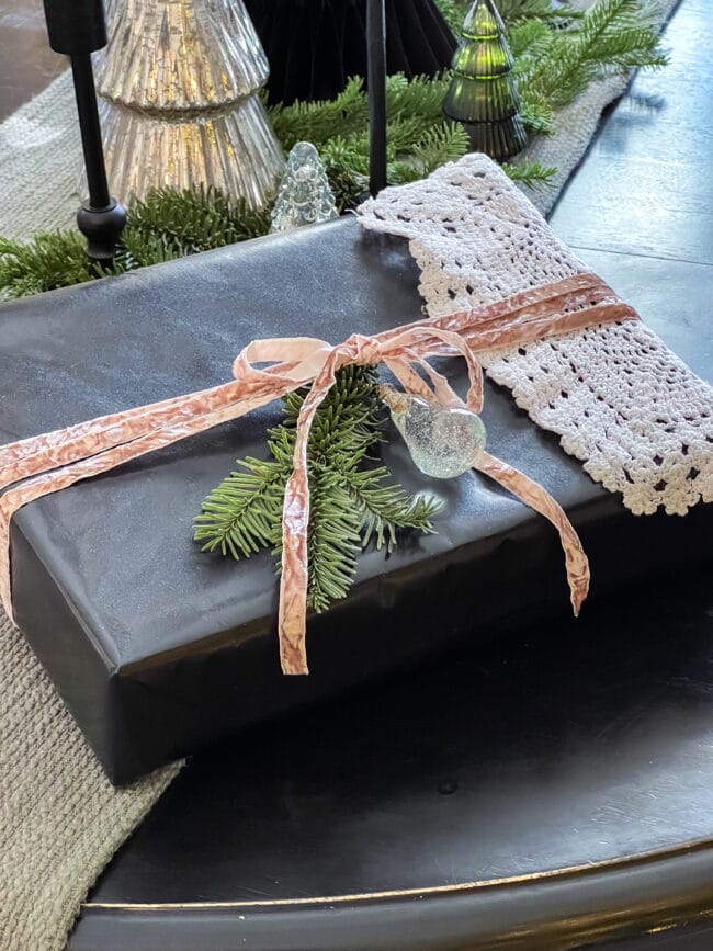 black gift box with taupe crushed velvet ribbon, clear glass ornament, doily and real greenery