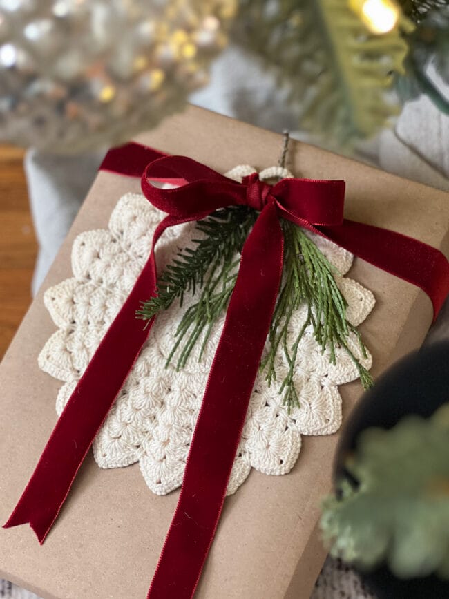 brown paper gift box with round doily, real greenery and deep red velvet bow