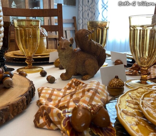 tablescape with a squirrel, acorns and gold glasses