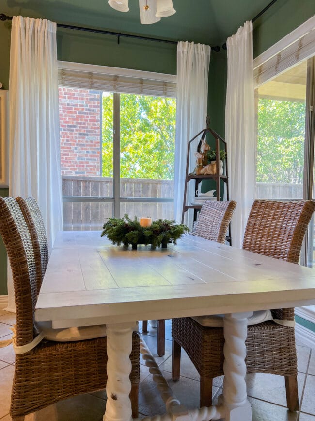 white kitchen table in front of windows with a candle centerpiece