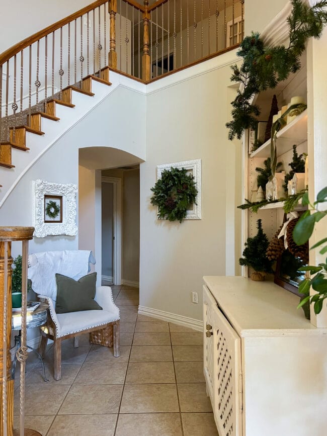 Entry in front of stairs with seating and frames with wreaths