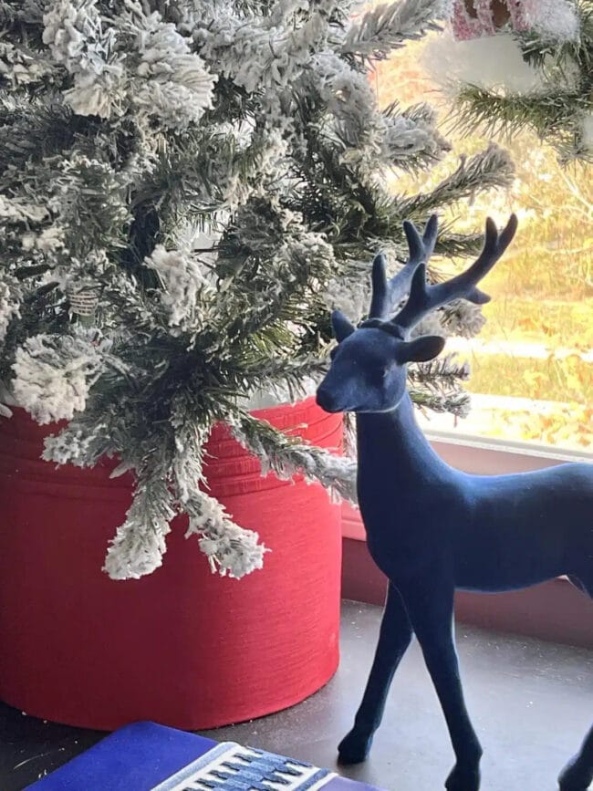 red lamp shade turned into a Christmas tree stand with a black deer sitting next to it.