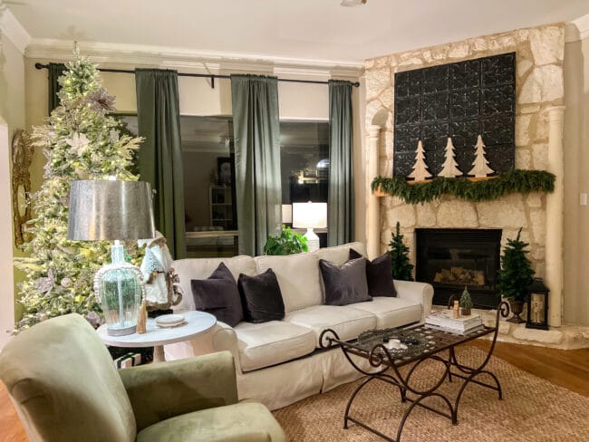 cozy living room during the evening with a white sofa, gray pillows a stone mantel and Christmas tree