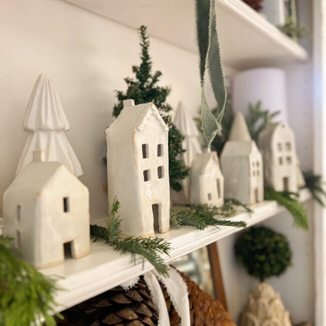 white handmade houses with live stems on the hutch shelf