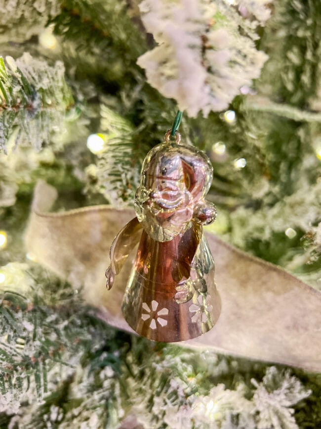 small silver Santa ornament hanging on a flocked Christmas tree