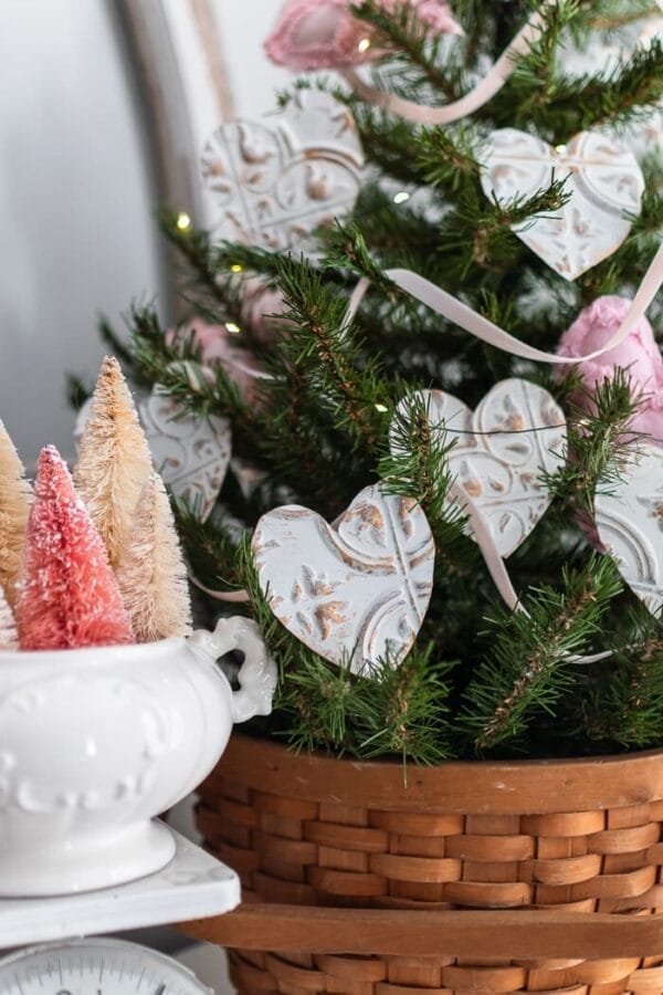 green tree with embossed metal cutout hearts and small pink bottle brush trees in ironstone bowl