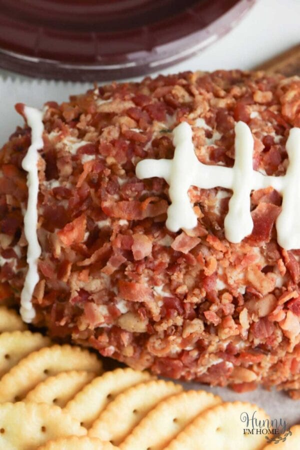 football shaped cheeseball made with bacon and has crackers on the side