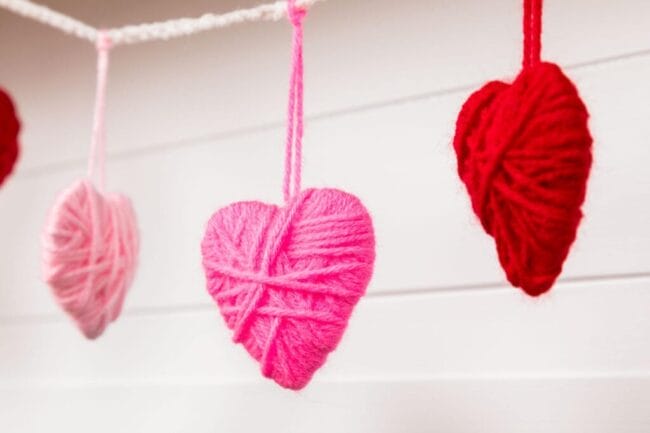 red and pink yarn hears hanging on a string