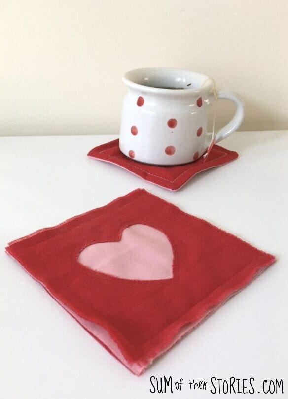 red and pink fabric coaster with a heart in the middle and a white coffee cup with red polkadots.