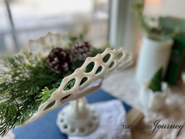 milk glass antique piece holding winter greens with pinecones